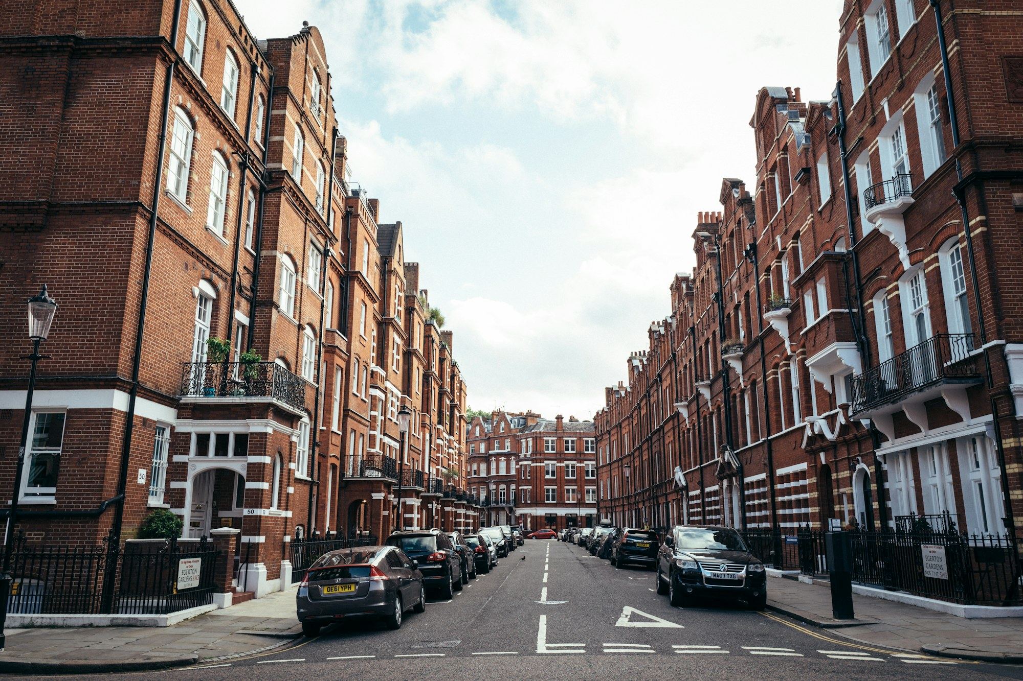 Red-brick terraced street of London houses with parked cars