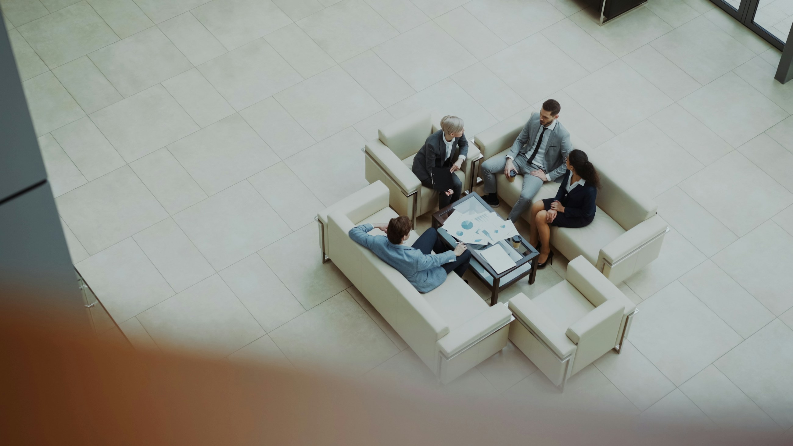 Four professionals discussing their work around a table in a light-filled atrium